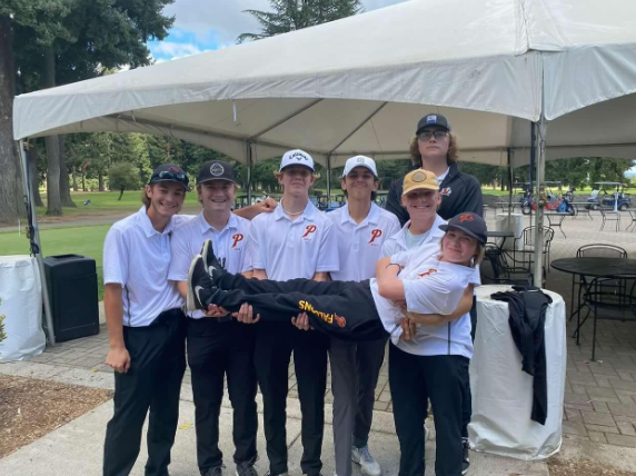 The boys pose at Glendoveer Golf course after their meet holding up sophomore Maverick. 