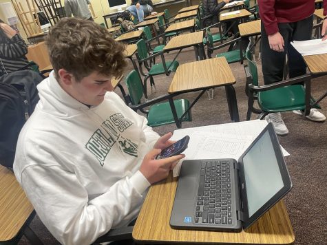 Student sits on his phone. 