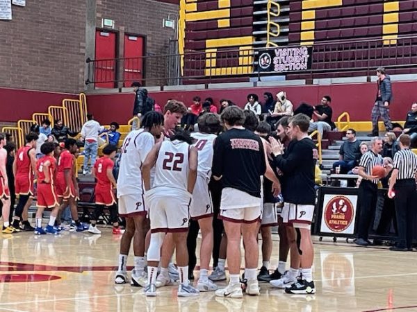 The 2023-2024 Prairie Basketball team in a huddle during a Varsity game.