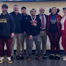 Wrestlers Tommie Vick and Faith Tarrant show off their medals while sharing a moment with their coaches.