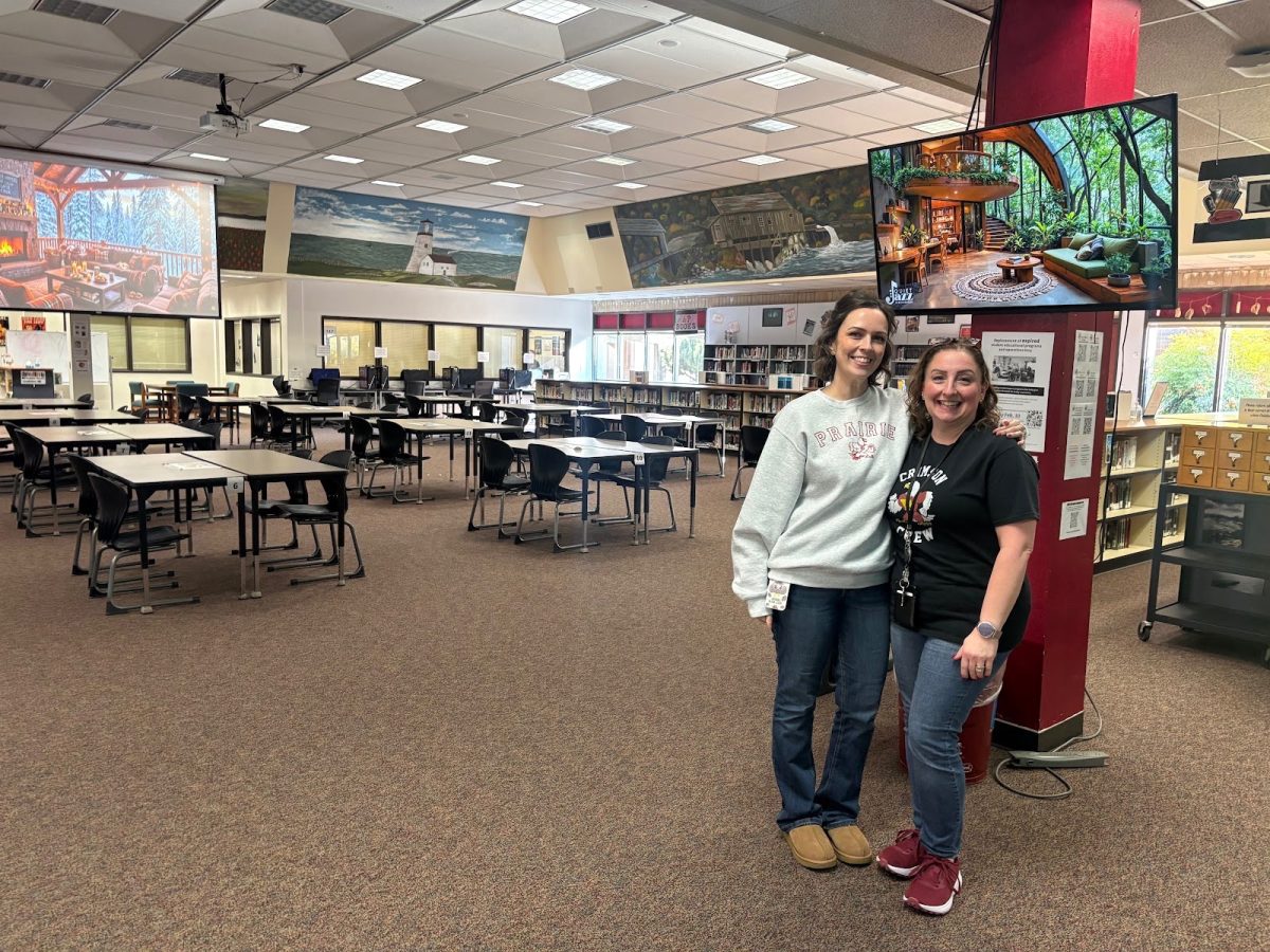  Lauren Lavender and Robin Brennan standing in the library.
