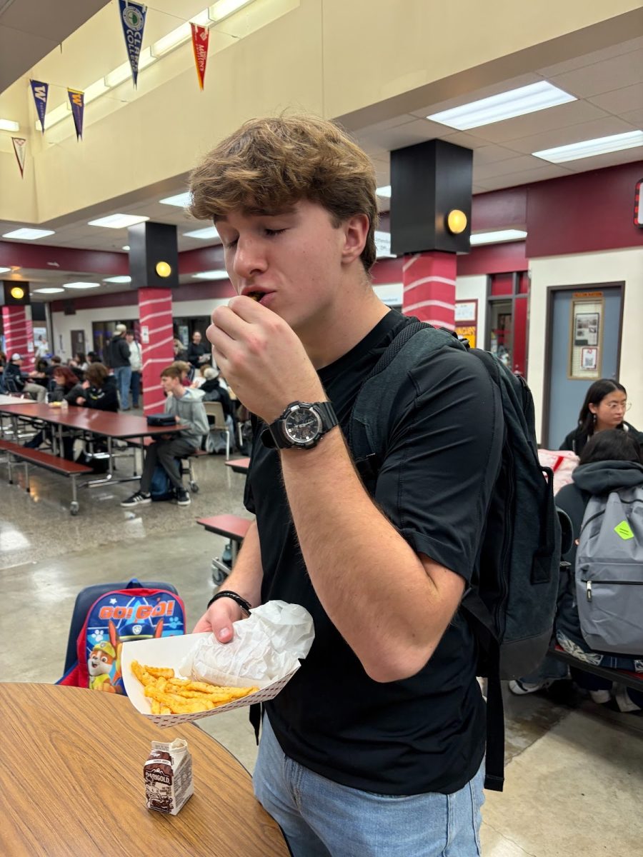 Senior Caleb Harr eating his Fries and Chicken burger from hot lunch.